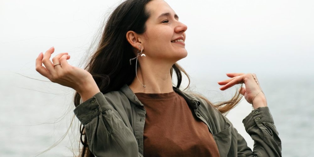 Candid portrait of a strong independent carefree woman with flowing hair against the background of the sea in autumn.